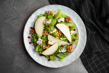 Delicious pear salad on dark textured table, top view