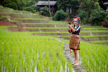 Asian Hmong Woman in Traditional Attire Using a Smartphone with copy space; The Fusion of Old and...