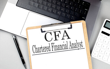 Paper clipboard with CFA on laptop with pen and calculator
