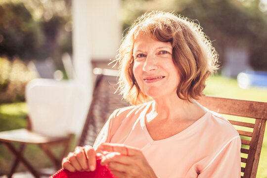 Older woman looking into the camera while knitting.