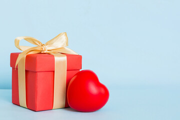 gift box with red bow and red heart on colored background. Perspective view. Flat lay