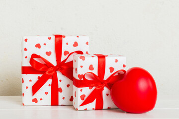 gift box with red bow and red heart on colored background. Perspective view. Flat lay
