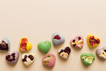 chocolate sweets in the form of a heart with fruits and nuts on a colored background. top view with space for text, holiday concept