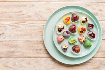 Plate with different chocolate on colored background. Assortment of fine chocolates top view vith copy space Health and obesity concept