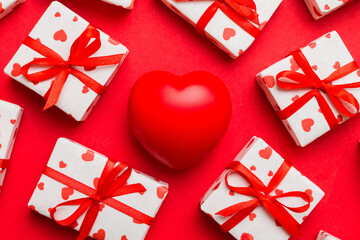 gift box with red bow and red heart on colored background . Top view. Flat lay