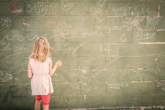Young girl drawing on a wall with chalk.