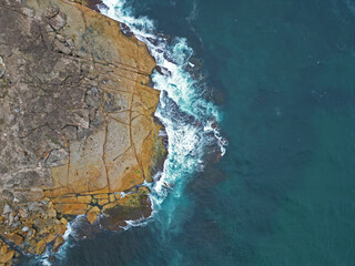 Aerial view of the rocky shore and blue waters. Freshwater, New South Wales, Australia