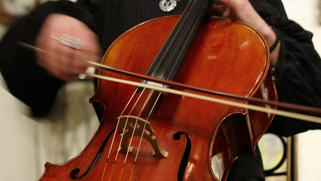 A man in a black shirt plays the cello.