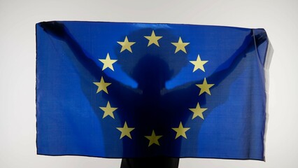 Person silhouette holding big flag against white background. Silhouette of man with national flag of European union holding in hands.