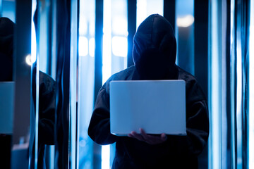 Male hacker in dark room using laptop internet hacking