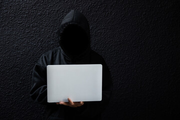 Male hacker in dark room using laptop internet hacking