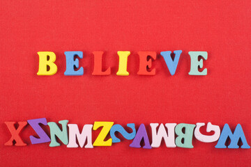 BELIEVE word on red background composed from colorful abc alphabet block wooden letters, copy space for ad text. Learning english concept.