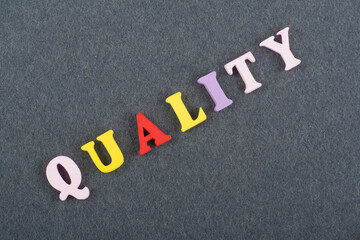 GUALITY word on black board background composed from colorful abc alphabet block wooden letters, copy space for ad text. Learning english concept.