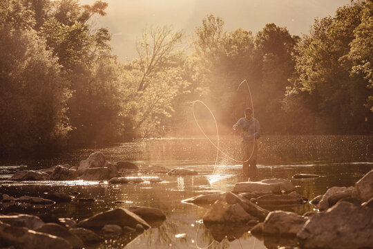 Fly fisherman fishing on river at sunset. Mozirje, Slovenia