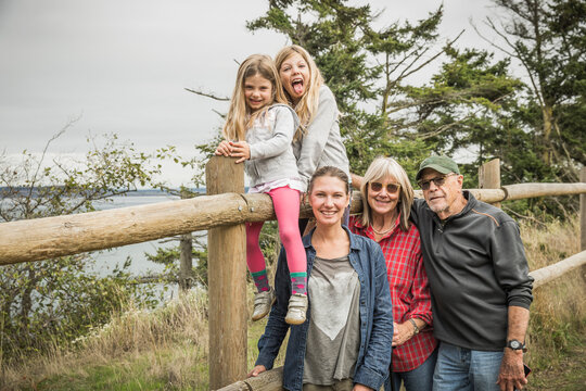 Mother, two daughters and grand parents posing for family picture along a fence. Port Townsend, Washington, USA