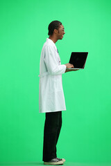A male doctor, on a green background, in full height, uses a laptop
