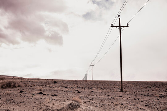 Long row of power signs with desert and gray clouds on the horizon. Olancha, California