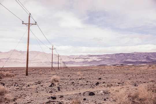 Long row of power signs with desert and gray clouds on the horizon. Olancha, California