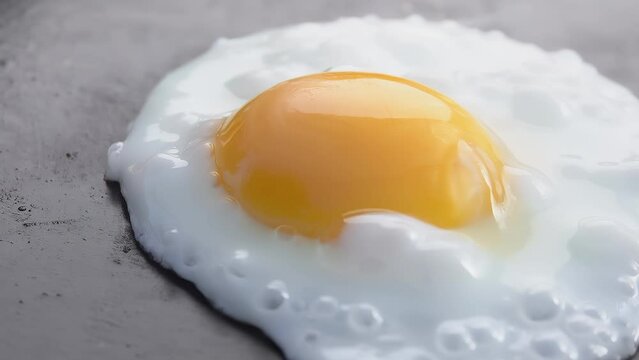 Super close-up of the fried egg taken from the flat grill surface outdoors
