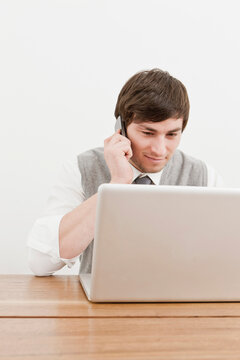 Young professional in business attire in an office of a small start up company with cell phone and, computer and documents. Munich, Germany