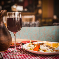 Greek salad and glass of red wine on the oak table