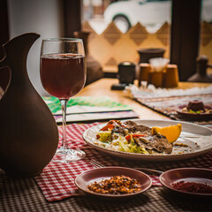 Greek salad and glass of red wine on the oak table