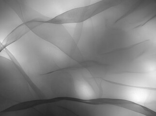 Grey light patches, blurred abstract background with shadows of highlighted tulle fabric with...