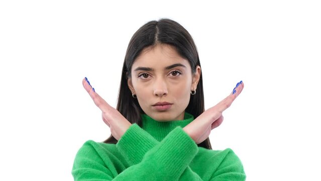 Confident woman showing stop sign with crossed arms in rejection on white background. Refuse, disagree, restriction, disapproval concept.