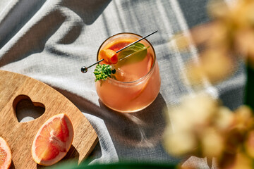 Summer refreshing grapefruit drink or alcoholic cocktail with grapefruit slices, ice and herbs....