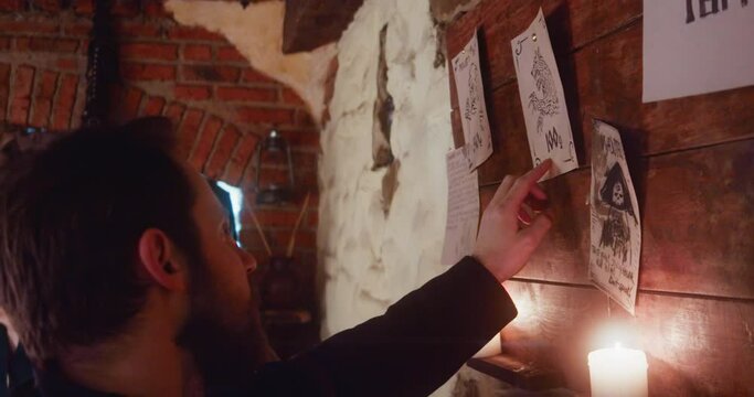 Men decide to hunt werewolf standing at bulletin board in tavern closeup. Adventurers hired to catch fantasy beast for reward visiting medieval guesthouse. Fantasy tale