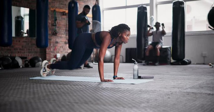 Black woman, fitness and mountain climber exercise on floor mat at gym for abdominal workout or training. Young African female person or athlete in core strength, ab muscle or balance at health club