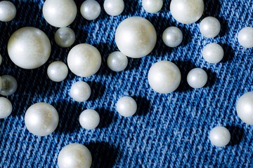 White pearls scattered on blue denim jeans texture background fashion design