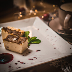 Cheesecake slice, New York style classical cheese cake on wooden background. Slice of tasty cake on white plate served with dessert fork