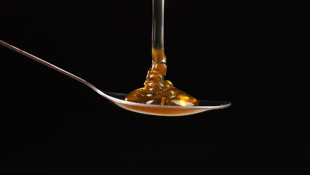 Honey Pouring Into A Spoon On The Black Background. Healthy Organic Thick Honey Closeup, Sweet Honey Dessert 4K
