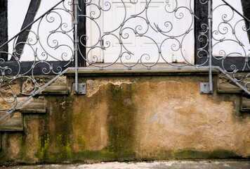 Alte verwitterte braune Steintreppe mit silbernem modernem Metallgeländer mit Muster vor...