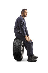 Profile shot of a mechanic sitting on a car tire