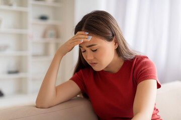 Fototapeta premium Portrait of stressed young asian woman with hand on her forehead