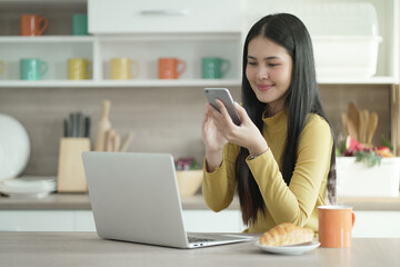 Asian Woman using mobile device and labtop at home. Social Media at Home. Young woman using the...