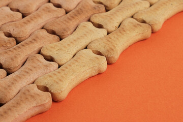 Fragrant biscuits for dogs and puppies in the shape of bones with the taste of meat on an orange background