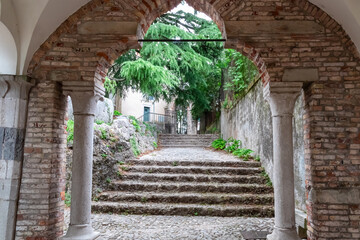 Stone archway with two stone pillar, leading to a narrow pathway lined with stone steps. Landmark...