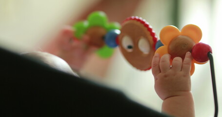 Baby hands playing with toy inside chair crib