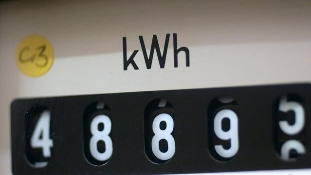A close-up of an electricity meter kWh symbol with shallow focus and energy consumption numbers. Concept for electric meter reading, fuel, heating, high bills and cost of living. Static shot.