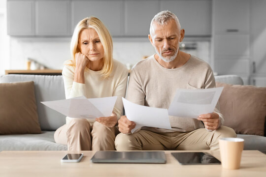 Worried Senior Spouses Reading Papers And Bills At Home