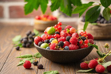 Various fresh berries in a bowl. Mix of different fresh berries on wooden background. Strawberries,...