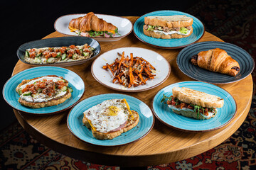 Dishes with sweet potato, sandwich, croissant and other dishes on a wooden table