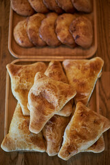 Fresh pastries on wooden plates: triangular samosas samosas with meat and sochen sochnik sweet made from shortcrust pastry, cottage cheese filling. national cuisine, Assortment of baked goods in cafe
