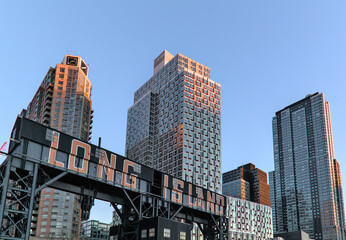 Long Island City sign on transfer bridges, support gantries, and piers in Gantry Park on the Queens waterfront in New York City with tall high rise residential buildings.