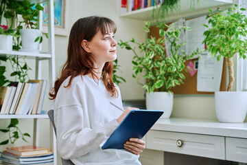 Young female teenager with digital tablet, stylus drawing illustrating sitting at home