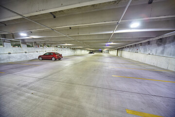 Solitary Red Car in Empty Indoor Parking Garage at Night