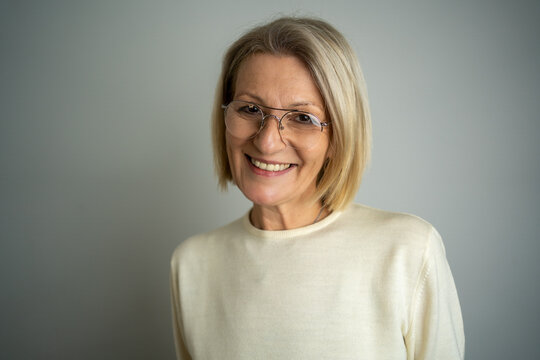 Image of happy senior business woman posing isolated over grey wall background. Copy space. Portrait of beautiful middle aged woman with blondie hair.